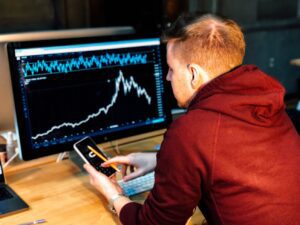 Young man using calculator and computer to graph data