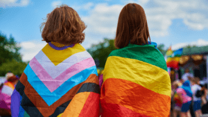 Two youth wrapped in banners of multiple colors representing diversity