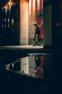 Teenager standing alone at night on street beneath a street lamp head lowered